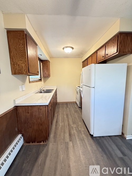 A kitchen with a white refrigerator and wooden cabinets.