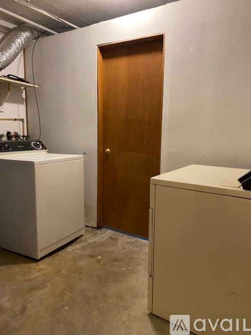 A room with a white cabinet, a white box, and a wooden door.