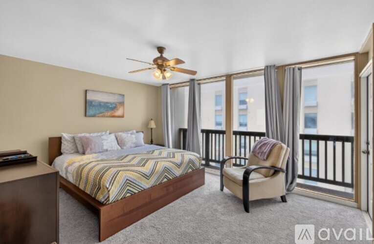 A bedroom with a large bed and a chair by the window.