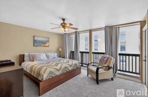 A bedroom with a large bed and a chair by the window.