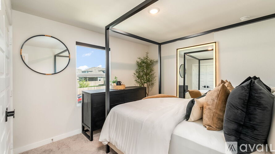 A bedroom with a bed, a mirror, and a plant.