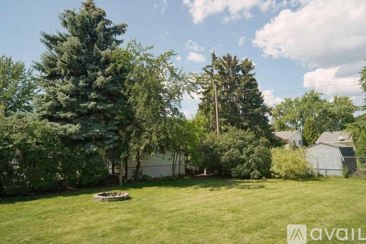 A backyard with a grassy area, trees, and a shed.