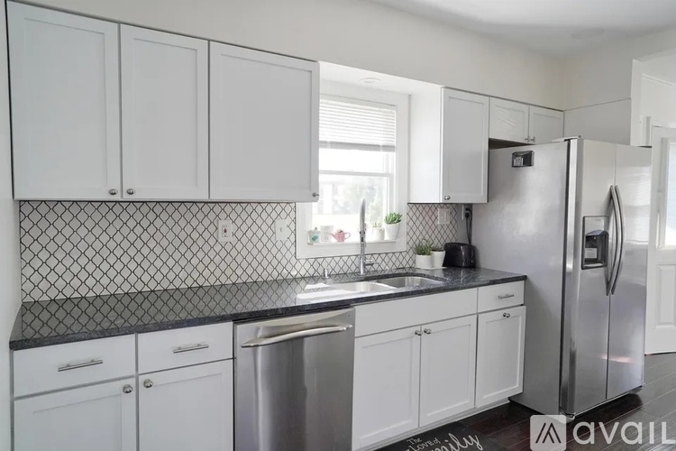 A kitchen with white cabinets and a black countertop.