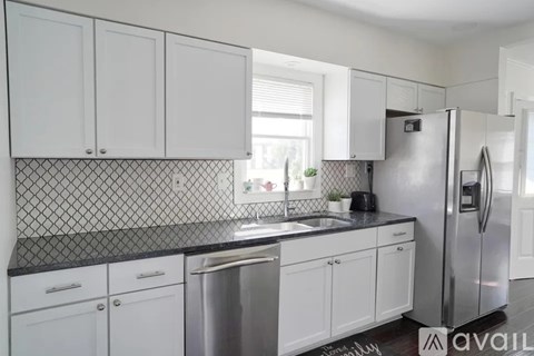 A kitchen with white cabinets and a black countertop.