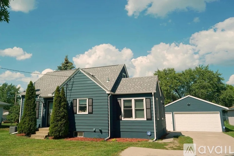 A blue house with a white garage door and a grey roof.