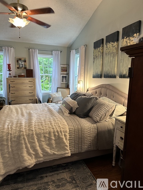 A bedroom with a large bed and a ceiling fan.
