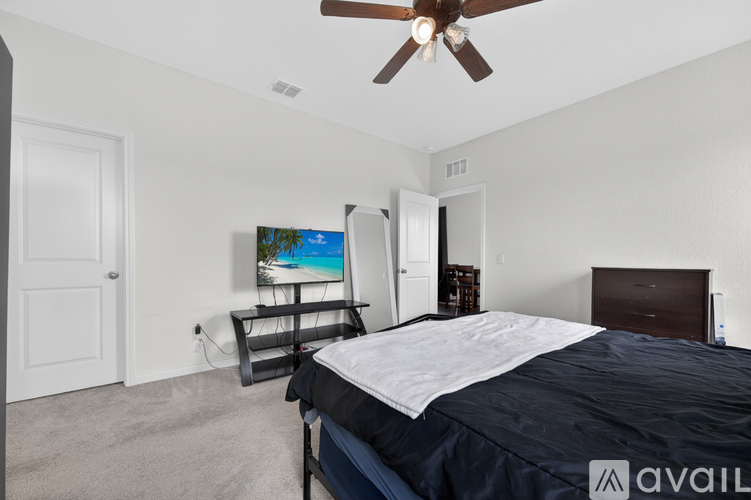 A bedroom with a bed, dresser, and a ceiling fan.
