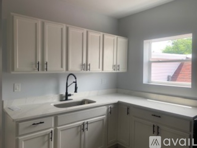A kitchen with white cabinets and a window.