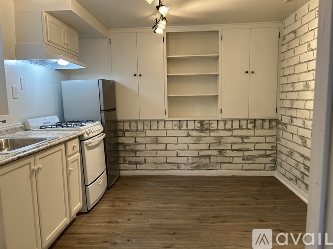 A kitchen with white cabinets and a brick wall.