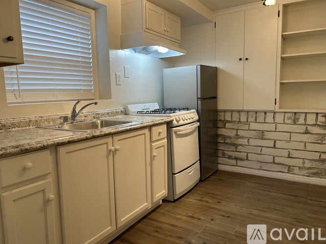 A kitchen with white cabinets and a brick wall.