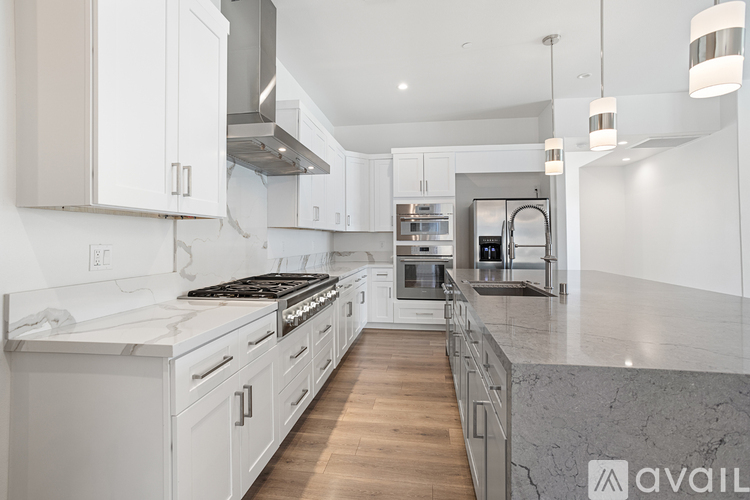 A modern kitchen with white cabinets and a marble countertop.