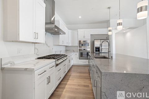 A modern kitchen with white cabinets and a marble countertop.