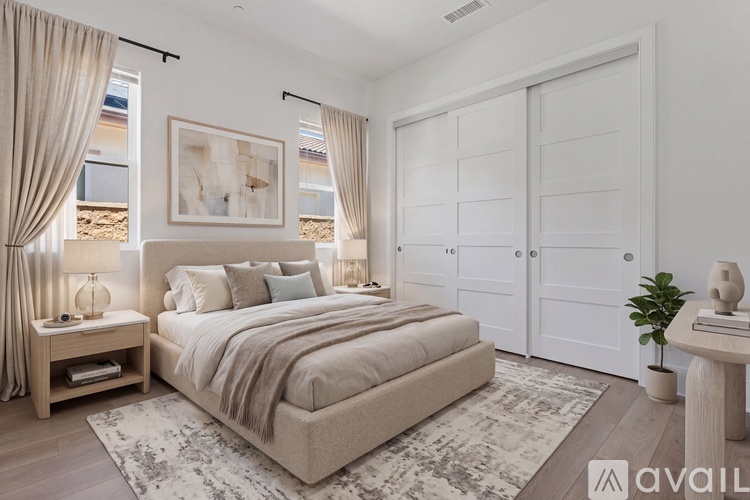 A bedroom with a large bed, a nightstand with a lamp, and a painting on the wall.