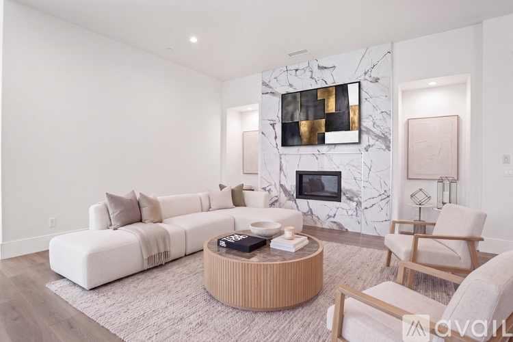 A living room with a white sofa, a coffee table, and a TV mounted on a marble wall.