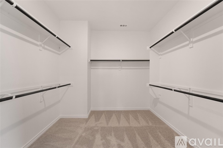 A spacious walk-in closet with white shelving and a carpeted floor.