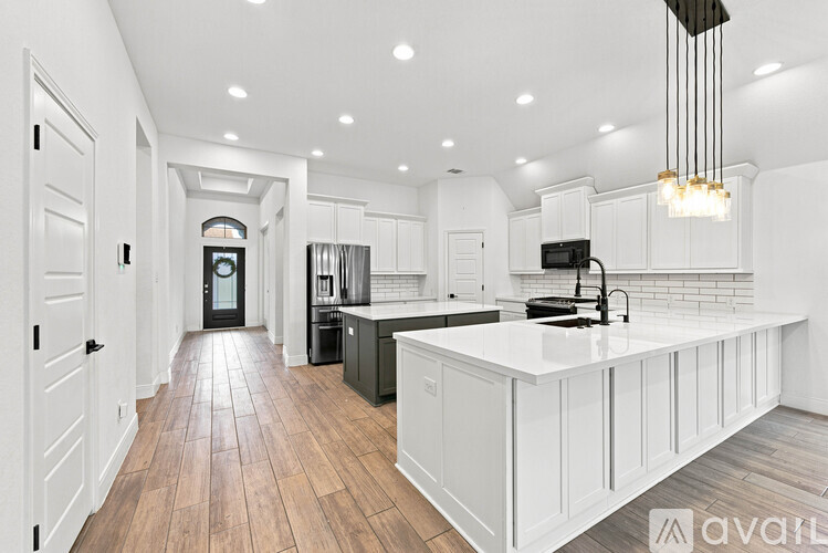 A modern kitchen with white cabinets and a wooden floor.