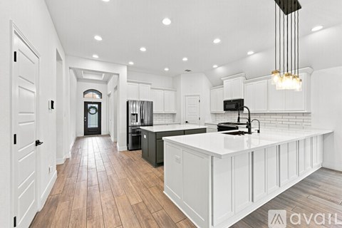 A modern kitchen with white cabinets and a wooden floor.
