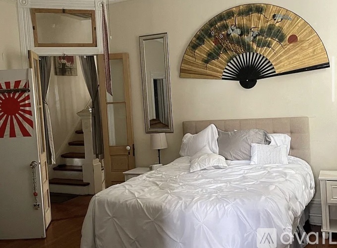 A bedroom with a large bed and a Japanese fan on the wall.