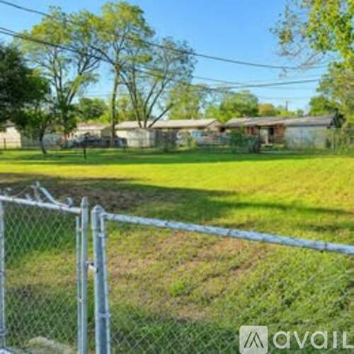 A chain link fence in front of a grassy area.