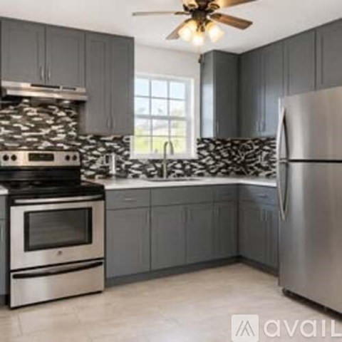 A modern kitchen with a stainless steel refrigerator and a black and white backsplash.