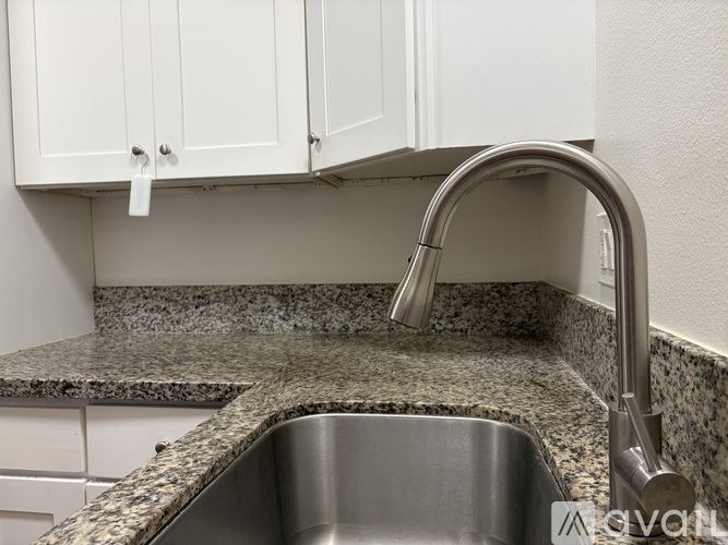 A kitchen with a granite countertop and a stainless steel sink.