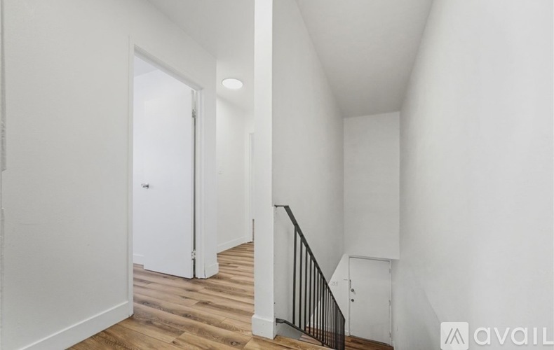 A hallway with a wooden floor and white walls.