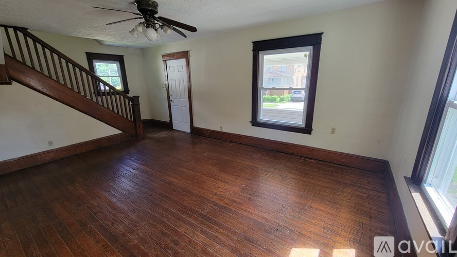 A room with wooden floors and a staircase leading to another room.