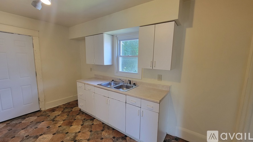 A kitchen with white cabinets and a tiled floor.