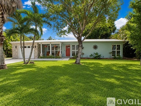 A house with a red door is surrounded by greenery.