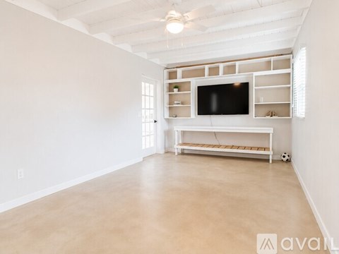 A spacious living room with a television and built-in shelves.