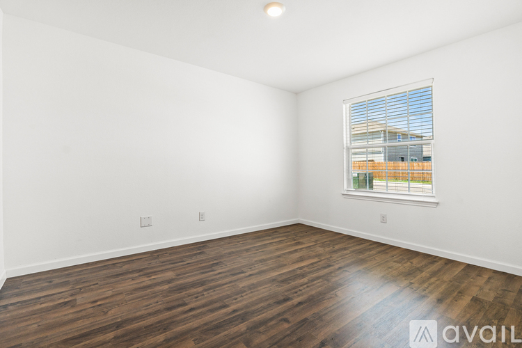 A room with wooden flooring and a window showing a building outside.