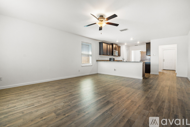 A spacious room with wooden flooring and a ceiling fan.