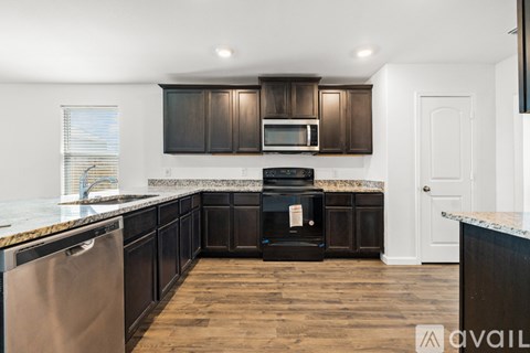 A kitchen with dark wood cabinets and a stainless steel dishwasher.