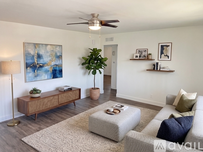 A living room with a white couch, a wooden cabinet, a rug, and a painting on the wall.