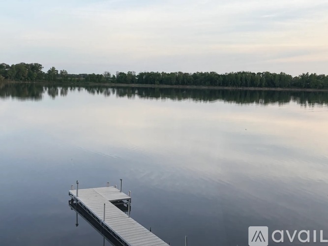 A dock extends into a calm lake with trees in the background.