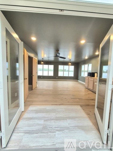 A spacious room with a ceiling fan and wooden flooring.