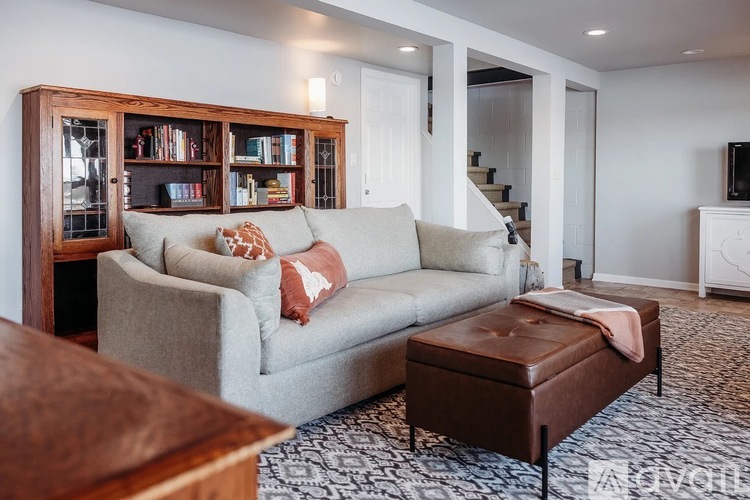 A living room with a grey couch and a brown ottoman.