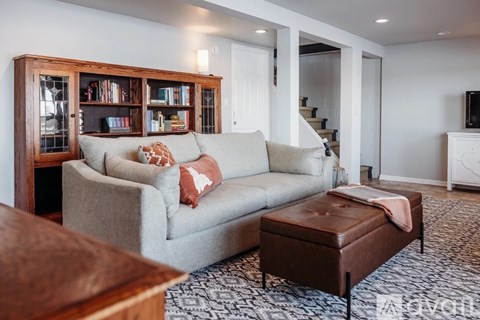 A living room with a grey couch and a brown ottoman.