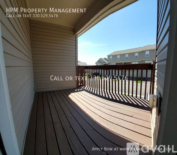 A wooden deck with a view of a building and a clear sky.