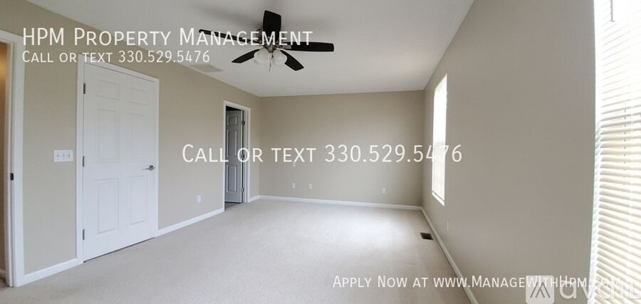 A spacious room with a ceiling fan and a door leading to another room.