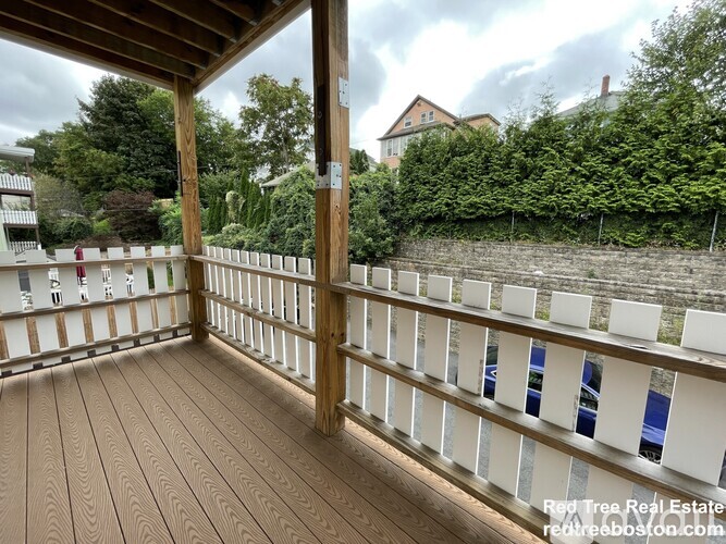 A balcony with a railing and a view of a building and trees.