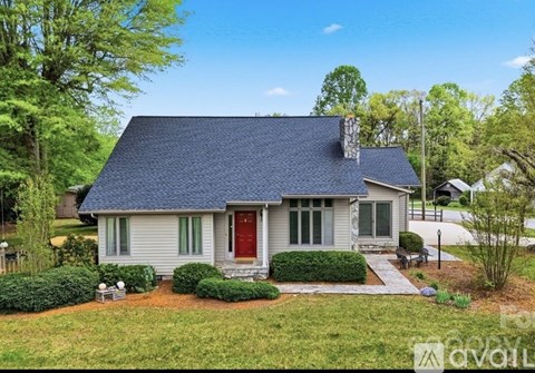 A house with a red door is surrounded by greenery.