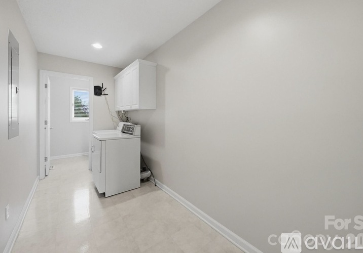 A small white kitchen with a refrigerator and a cabinet.