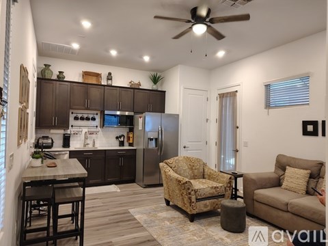 A living room with a couch, chair, and a kitchen area with a refrigerator and stove.