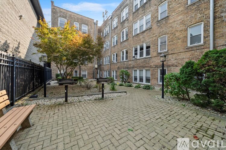 A brick courtyard with a bench and a tree in front of a brick building.