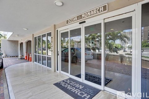 The entrance to the Ocean Monarch building with glass doors and a doormat.