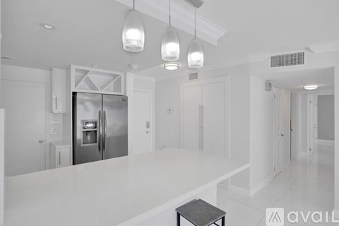 A modern kitchen with a stainless steel refrigerator and a black stool.
