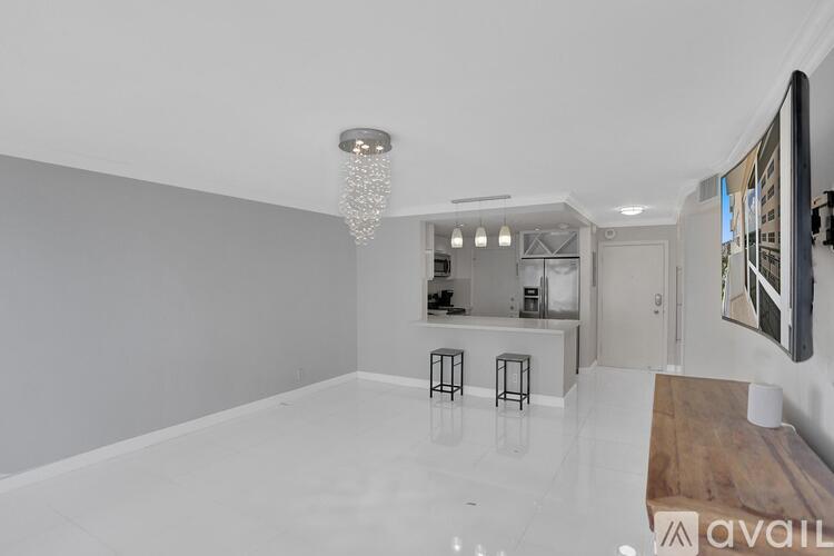 A spacious, white-walled room with a bar area and a television.