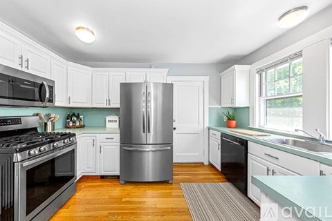 A kitchen with a stainless steel refrigerator and wooden floors.
