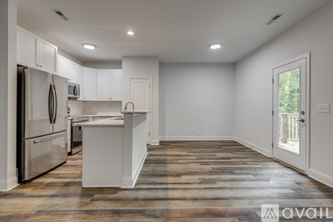 A kitchen with white cabinets and a wooden floor.